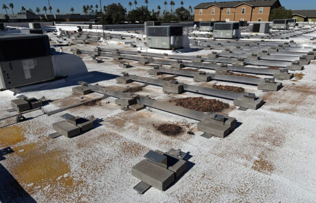 Large commercial rooftop with multiple HVAC units and visible wear patterns across surface of the building