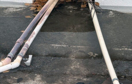 Roof drainage outlet blocked by debris and piping causing water backup risk