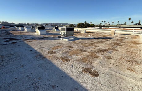Commercial flat roof inspection showing worn coating, debris buildup, and surface deterioration.