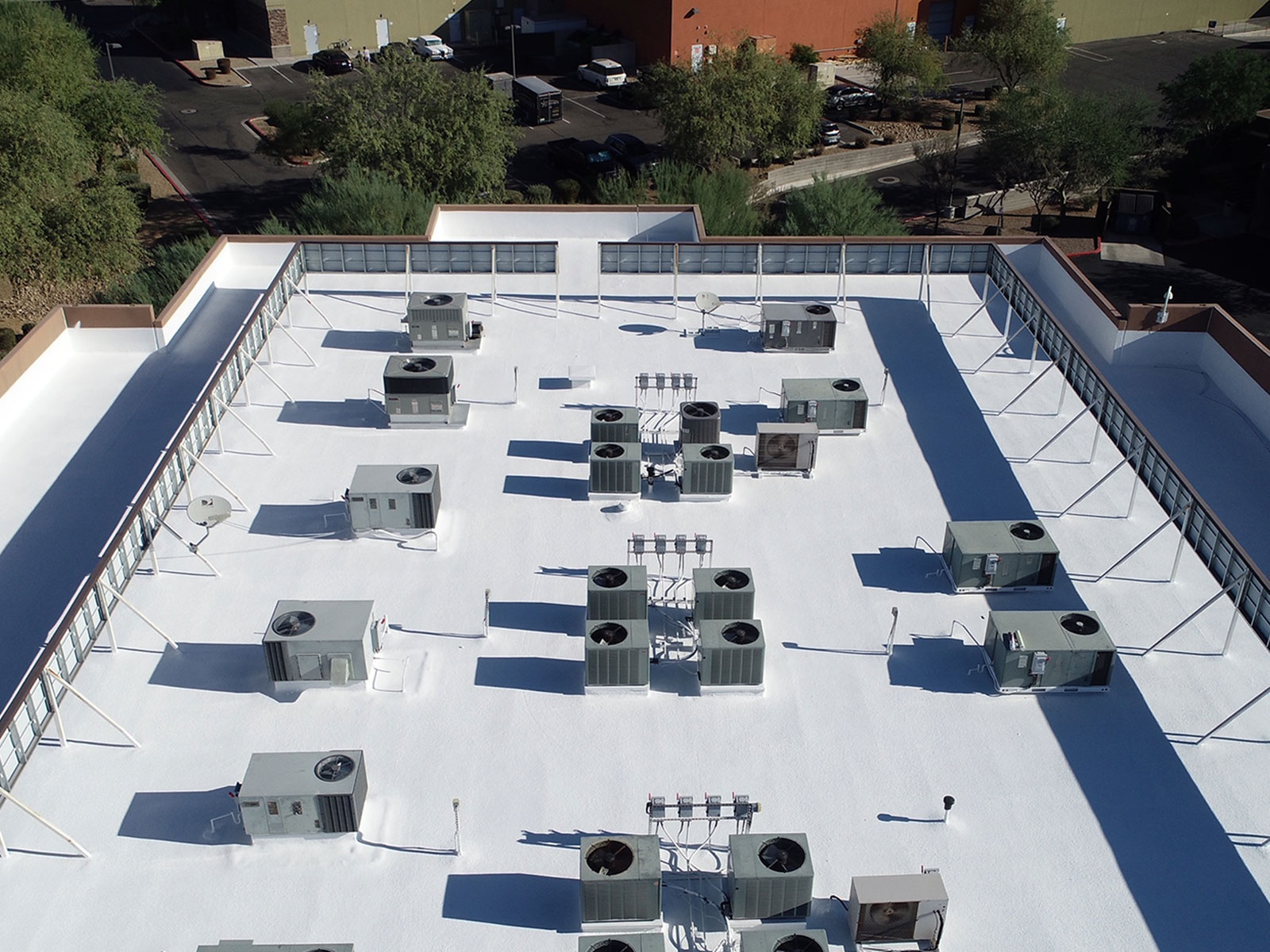 Commercial foam roof with HVAC equipment requiring long-term maintenance and budgeting in Arizona Maintained commercial foam roof with white protective coating in Arizona