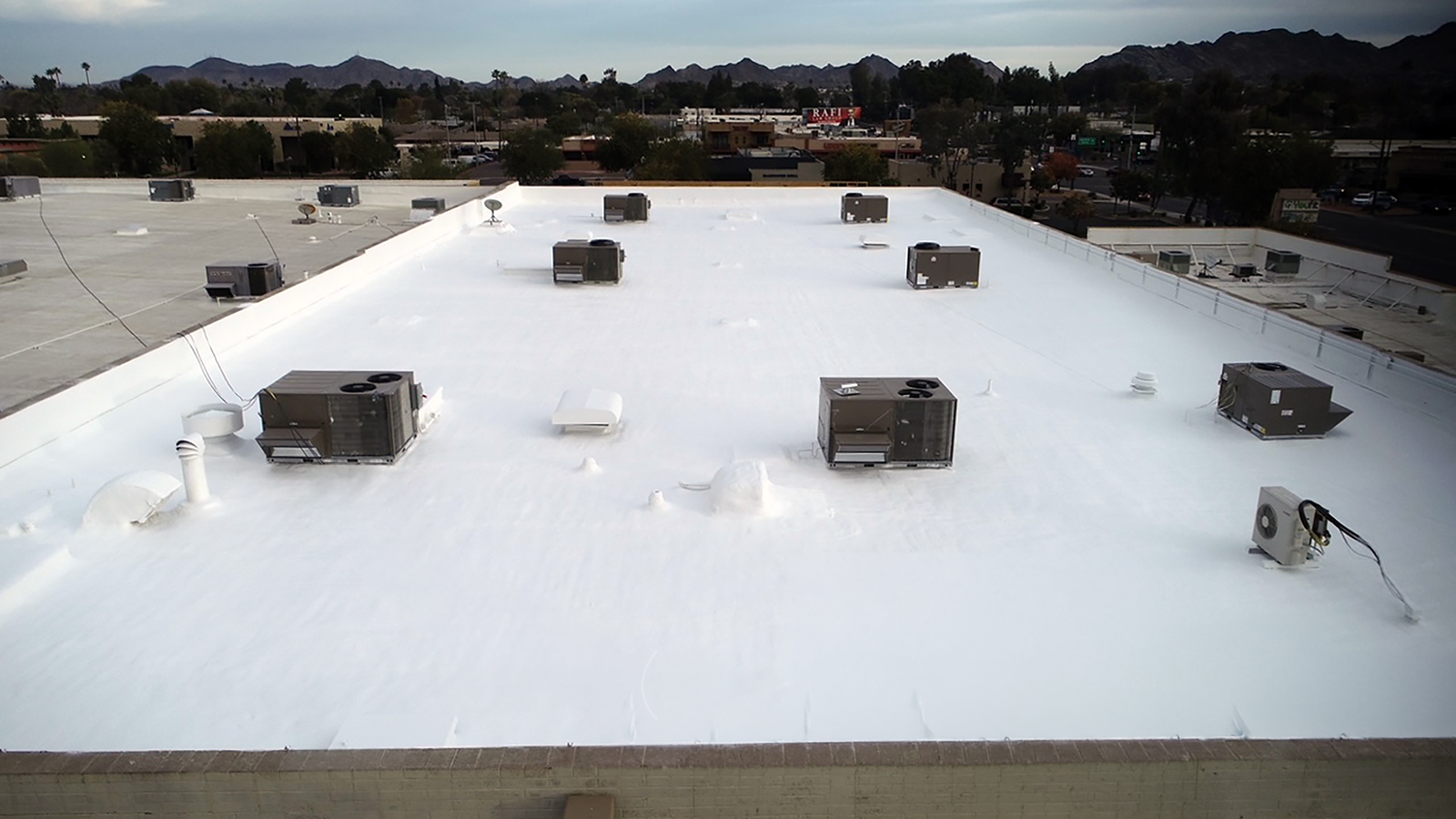 Commercial foam roof replacement in Phoenix AZ on flat building with rooftop HVAC units